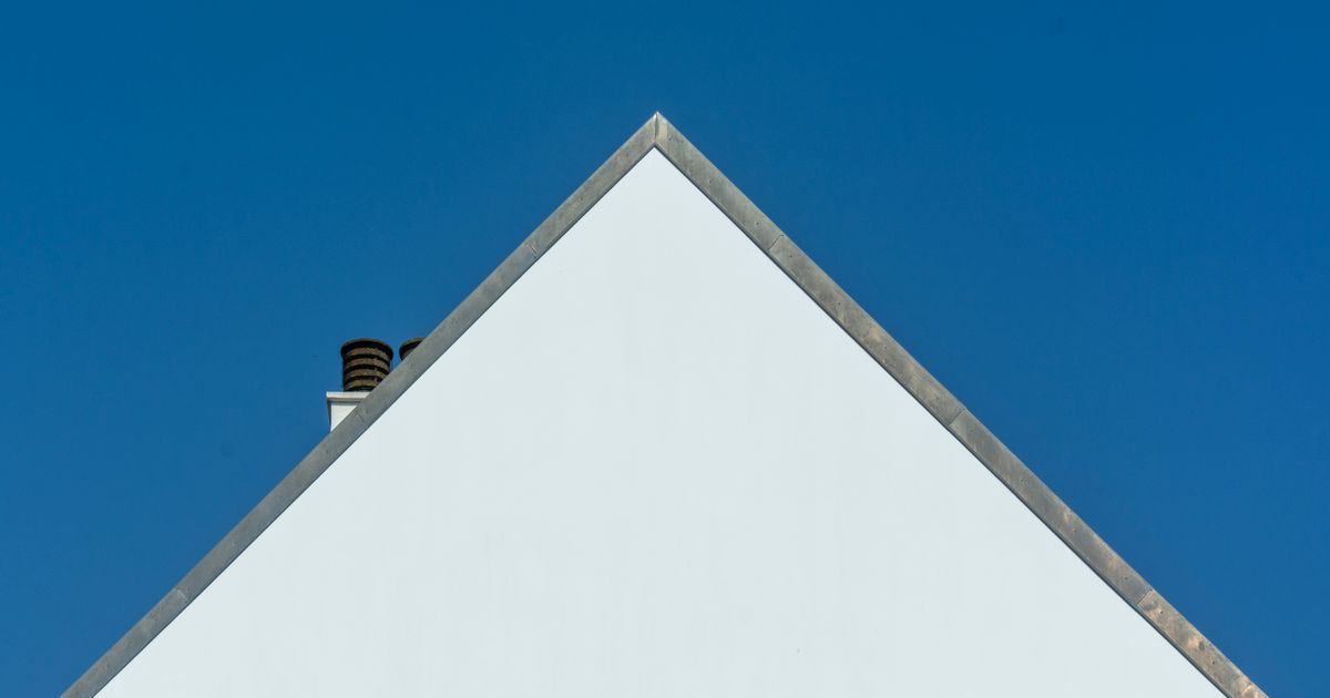青空を背景にした白い住宅の切妻屋根(イメージ)