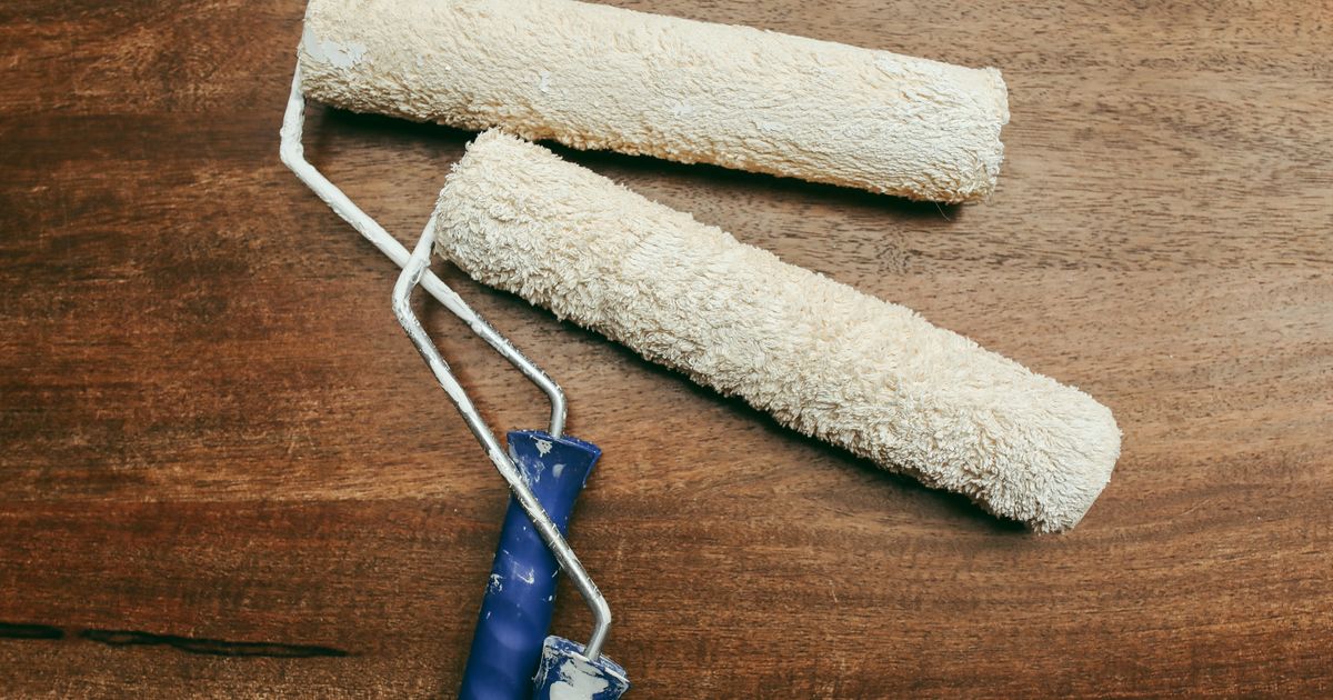 木製の台の上に置かれた2本の塗装用ローラー(イメージ)