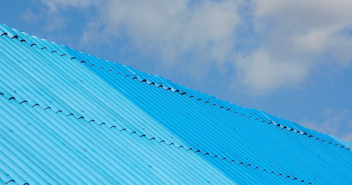 青空の下の青い波板トタン屋根(イメージ)